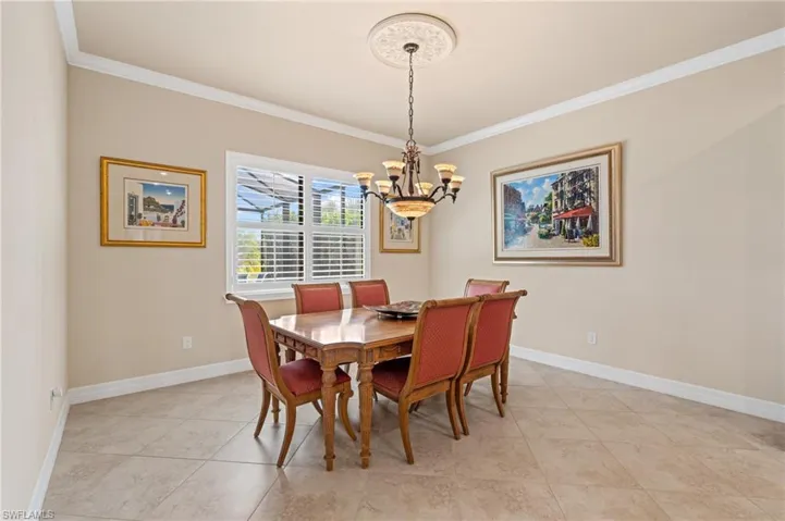 Dining space with ornamental molding, light tile patterned flooring, a notable chandelier, and baseboards