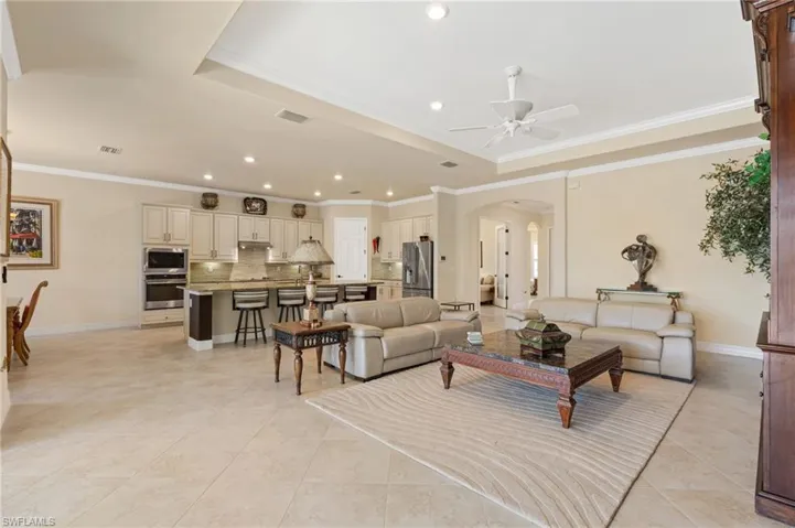 Living room featuring arched walkways, a tray ceiling, visible vents, and baseboards