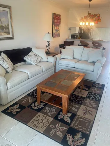 Living room with tile patterned floors, a notable chandelier, and ornamental molding