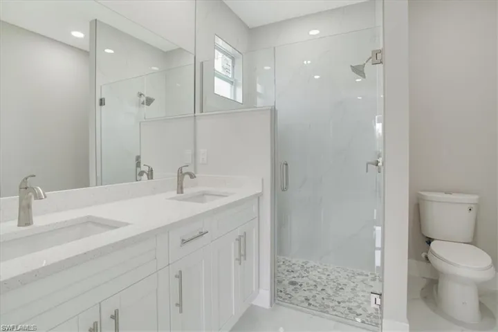 Bathroom featuring vanity, toilet, and an enclosed shower