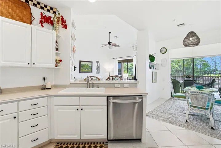 White cabinetry, light countertops, stainless steel appliances, ample storage, and a breakfast bar for casual dining.