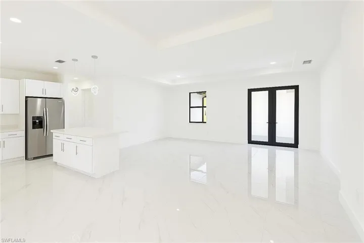 Unfurnished living room with french doors, recessed lighting, and a tray ceiling