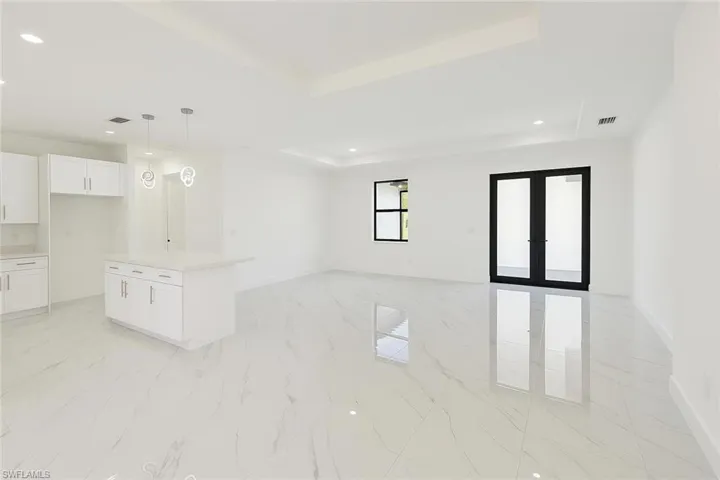 Unfurnished living room with french doors, recessed lighting, light marble finish floors, and a raised ceiling