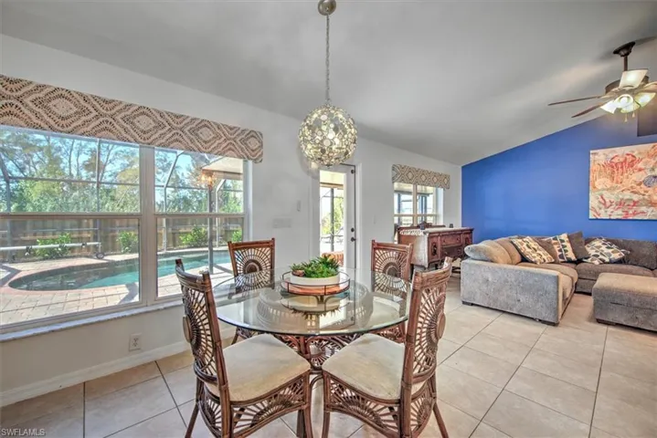 Dining area with lofted ceiling and fan, baseboards, and tile floors.