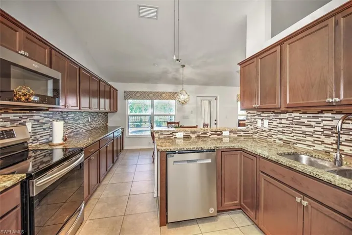 Kitchen with tile floors, stainless steel induction stove / convection oven / microwave, and dishwasher, a peninsula, a sink, and decorative tile backsplash.  Look at all of this storage space the kitchen gives you.