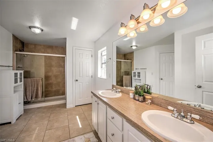Primary bathroom with double vanity, tile patterned flooring, a tile shower stall.