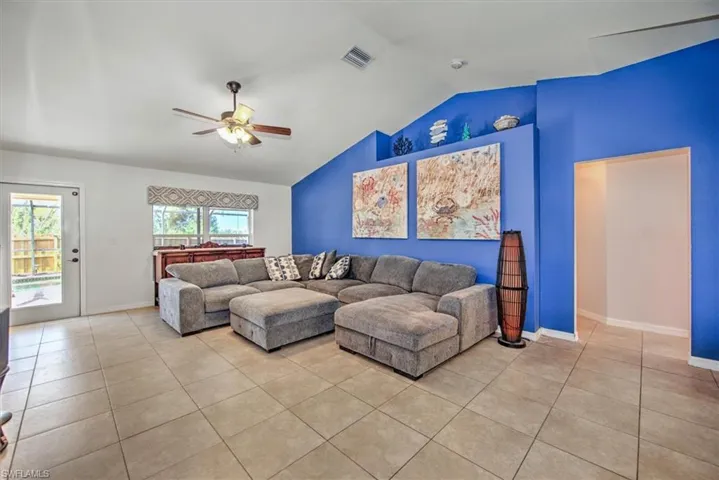 Living room featuring high vaulted ceiling with fan and tile floors.