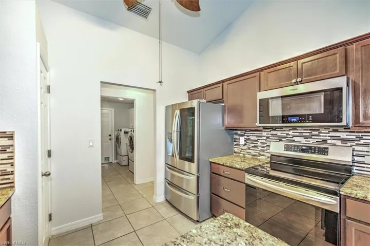 Kitchen with stainless steel induction stove /convection oven, upgraded refrigerator and connecting washer and dryer / utility area.