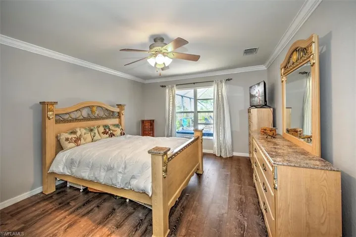 Primary bedroom with LVP flooring, and crown molding.