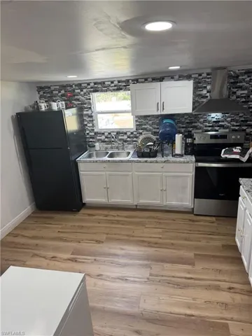 Kitchen featuring wood-finish flooring and white cabinetry