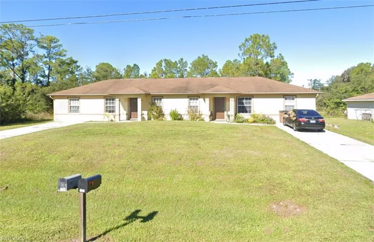 Single story home featuring a front yard, stucco siding, and concrete driveway