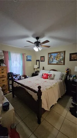 Tiled bedroom featuring a ceiling fan and a textured ceiling