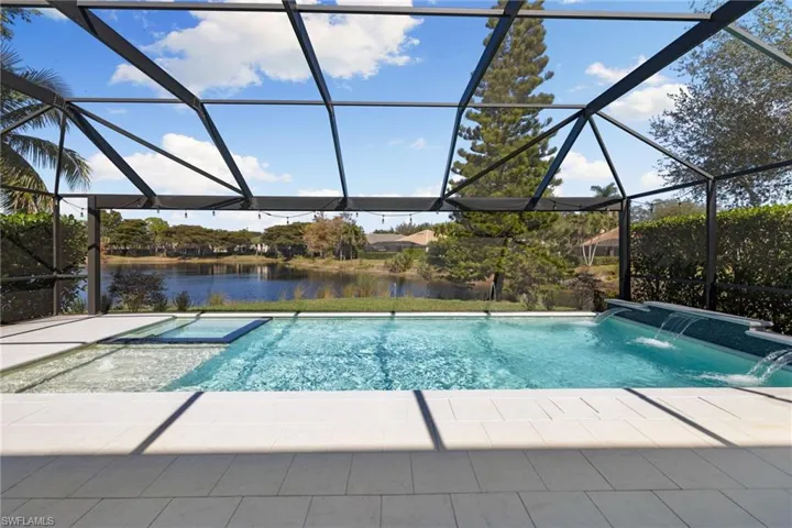 View of swimming pool with a sunroom, a lanai, a pool with connected hot tub, and a water view