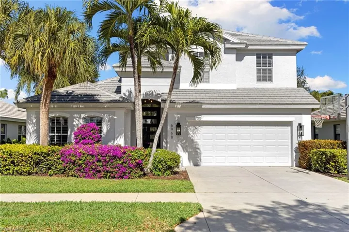 Traditional-style house featuring a garage, stucco siding, driveway, and a tiled roof