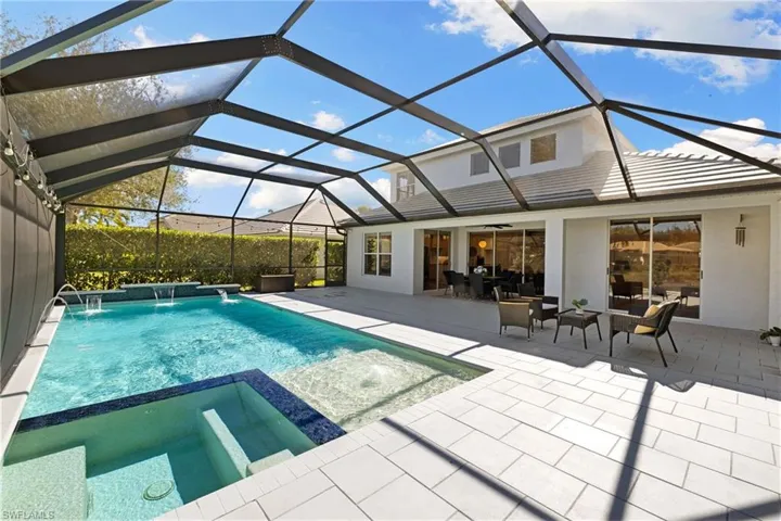 View of pool featuring a sunroom, a pool with connected hot tub, a lanai, and a patio