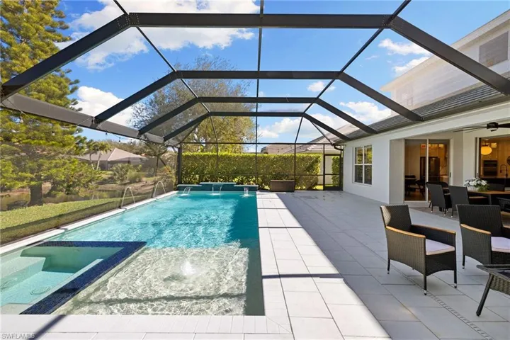 View of pool with a pool with connected hot tub, a sunroom, a lanai, a patio, and outdoor dining space