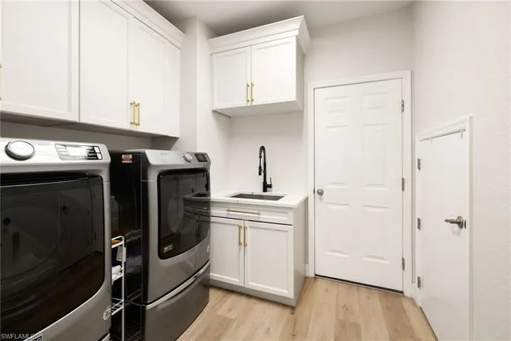 Laundry room with light wood-type flooring, washer and clothes dryer, and cabinet space