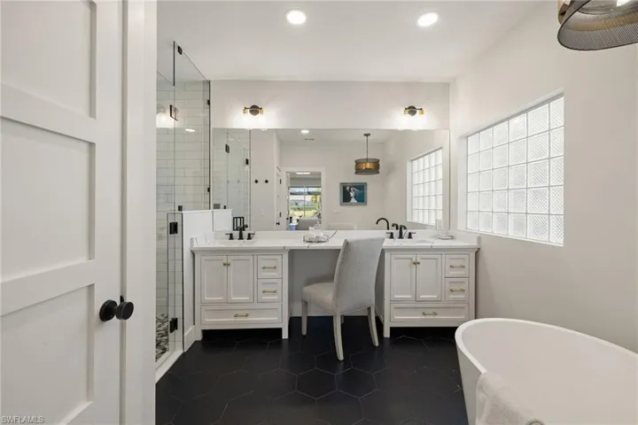 Primary Bathroom featuring a freestanding tub, dark tile patterned floors, double vanity, a stall shower, and recessed lighting