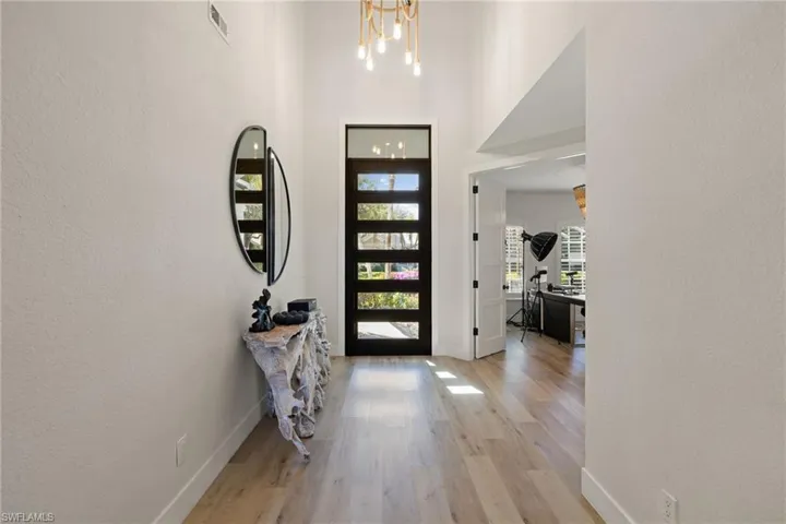Foyer entrance with a textured wall, light wood-type flooring, and a high ceiling