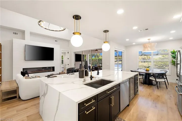 Kitchen with open floor plan, light wood-type flooring, decorative light fixtures, light stone countertops, and recessed lighting