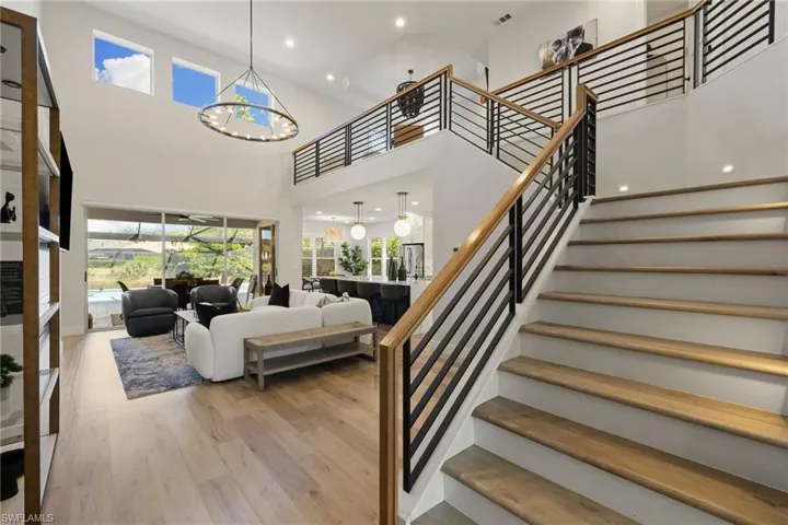 Stairway with plenty of natural light, recessed lighting, wood finished floors, a high ceiling, and a chandelier