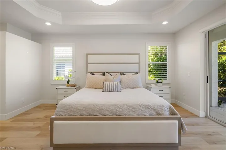 Primary Bedroom featuring access to outside, crown molding, recessed lighting, a raised ceiling, and light wood-style floors