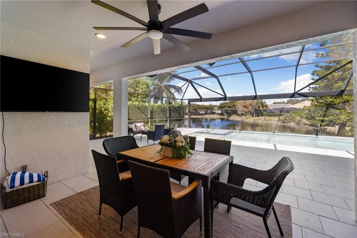 View of patio featuring a sunroom, a ceiling fan, glass enclosure, an outdoor pool, and a water view