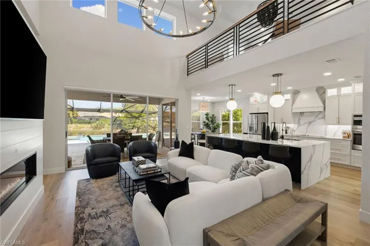 Living area with a sunroom, light wood finished floors, a chandelier, and a glass covered fireplace