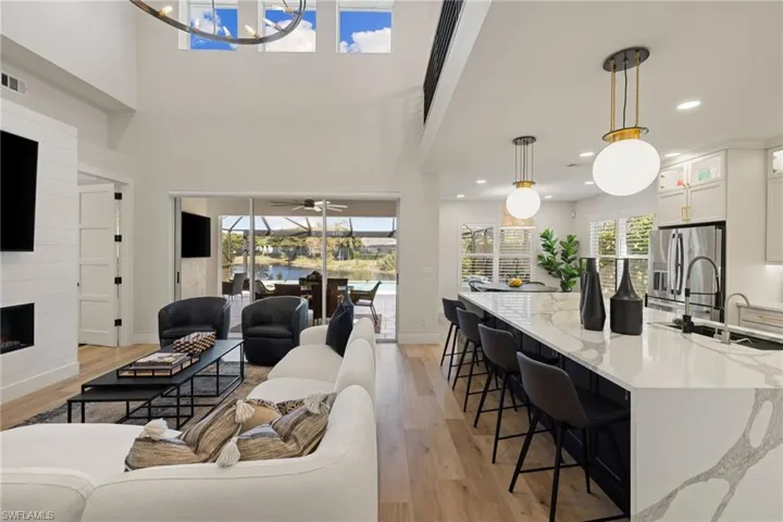 Living room featuring light wood-style flooring, a sunroom, a large fireplace, and recessed lighting