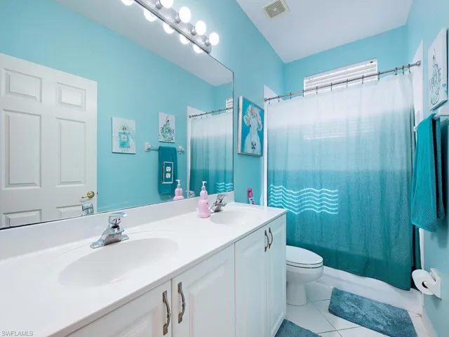 Bathroom featuring double vanity, light tile patterned flooring, and shower / bath combo