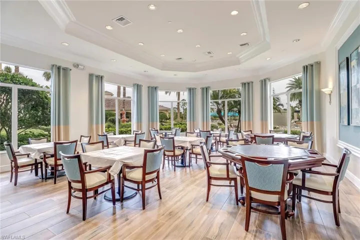 Dining room featuring light wood-style floors, a raised ceiling, plenty of natural light, and ornamental molding