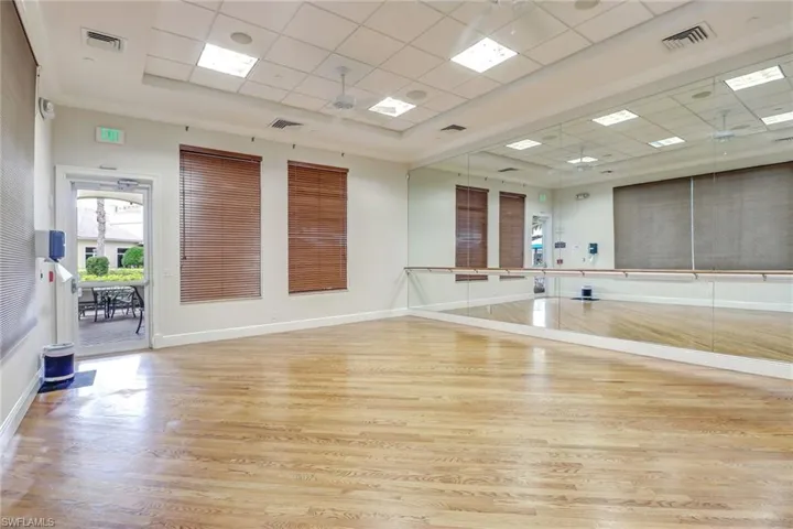 Workout room with a ceiling fan and a drop ceiling