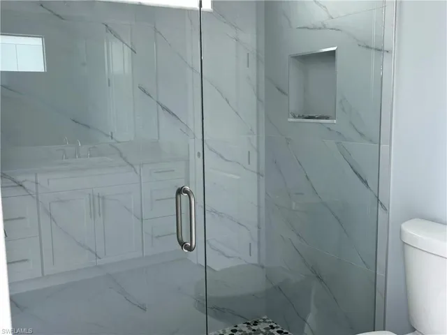 Bathroom featuring toilet, a shower with door, and sink