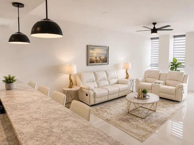 Open-concept living space featuring a long countertop with seating, two pendant lights, and a ceiling fan