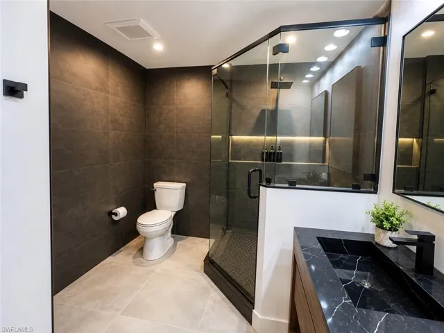 Modern bathroom featuring a glass-enclosed shower with a rainfall showerhead, integrated linear lighting, and a built-in niche