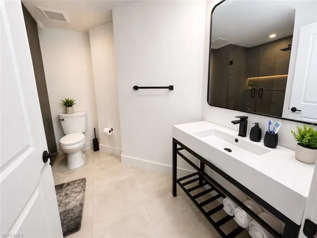 Contemporary bathroom featuring a black-framed vanity with integrated sink, matte black hardware, and an oversized mirror