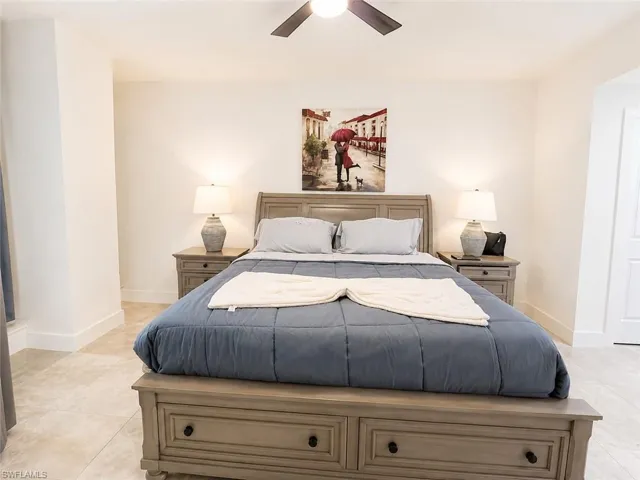 Bedroom featuring a ceiling fan with integrated lighting, tile flooring, and a paneled door