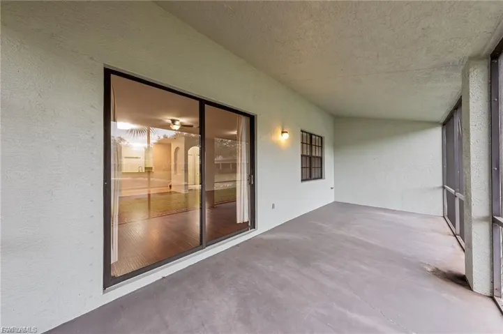 Screened porch featuring a concrete floor, textured walls, and a sliding glass door