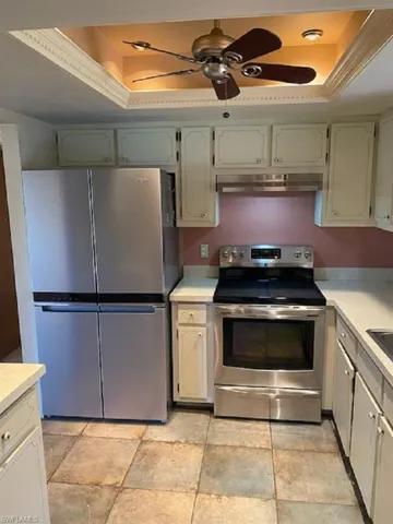 Kitchen with light countertops, stainlesssteel refrigerator,stove top range, dome ceiling with ceiling fan.