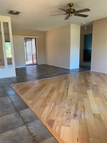 Family room / dinning room areas.  baseboards, a textured ceiling, visible vents, ceiling fan, and wood-type flooring