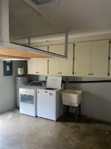 Washroom featuring washer dryer and abundant cabinet space and utility sink.
