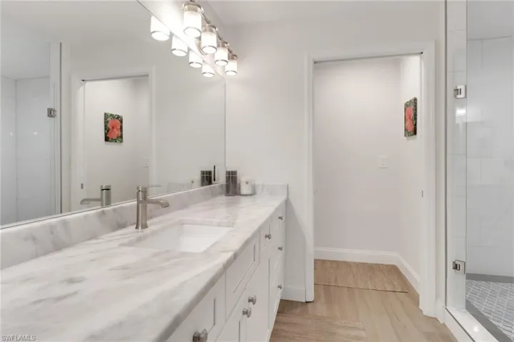 Bathroom with vanity, a stall shower, and light wood-type flooring