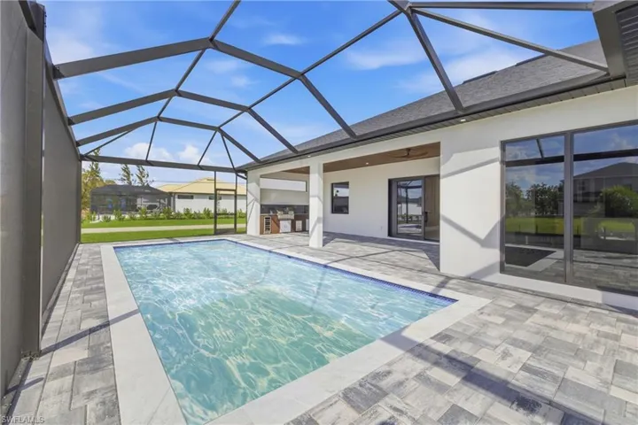 Outdoor pool featuring a sunroom, glass enclosure, and a patio area
