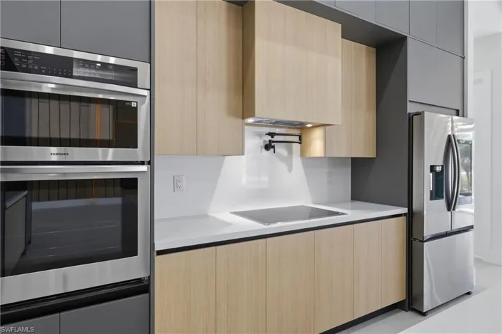 Kitchen with modern cabinets, stainless steel appliances, light wood finish cabinetry, and light stone counters