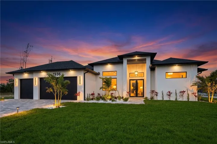 View of front facade featuring a front yard, stucco siding, and decorative driveway