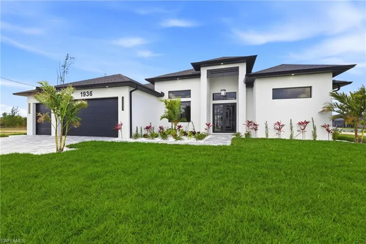 Prairie-style home featuring a front lawn, stucco siding, decorative driveway, and an attached garage