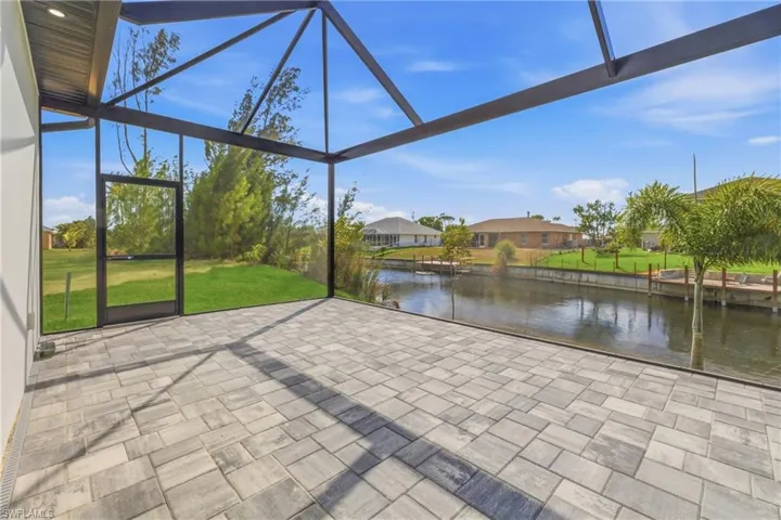 Unfurnished sunroom with a water view, a patio area, and a residential view