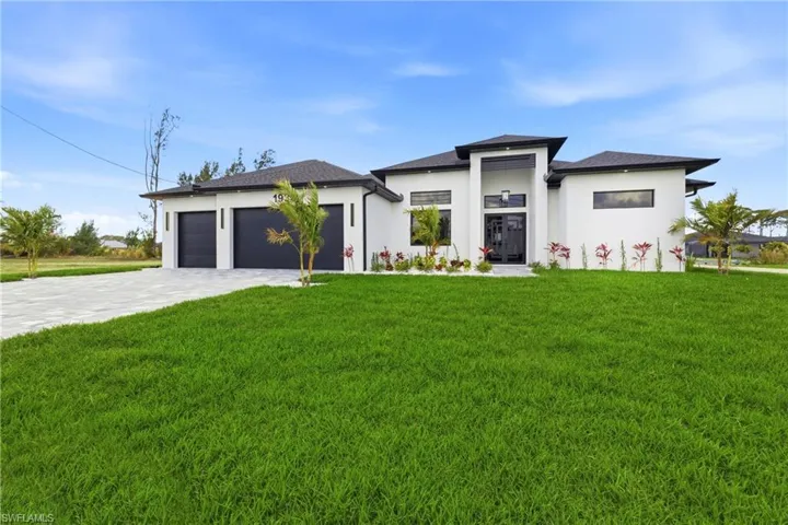 Prairie-style home with a front yard, stucco siding, decorative driveway, and an attached garage