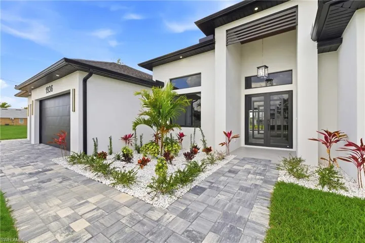 Doorway to property featuring french doors, stucco siding, a garage, and driveway
