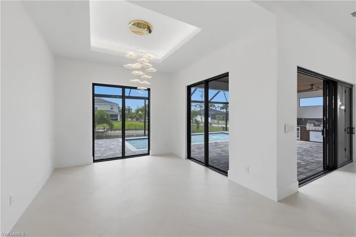 Empty room with suspended lighting, a raised ceiling, and a sunroom